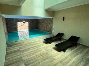 uma piscina com duas cadeiras pretas num quarto em HOTEL PORTELÃO no Rio de Janeiro