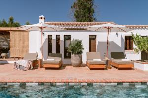 a pool with chairs and umbrellas next to a house at San Roque Suites de Monda in Monda