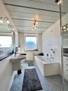 ein Badezimmer mit zwei Waschbecken, einer Badewanne und einem Fenster in der Unterkunft Charmantes Landhaus in Oberteuringen