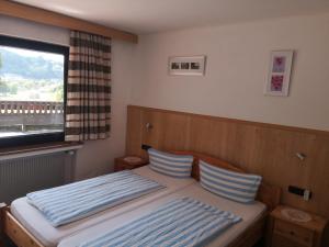 Schlafzimmer mit einem Bett mit blau-weißen gestreiften Kissen in der Unterkunft Hotel Finkenberg in Blankenheim