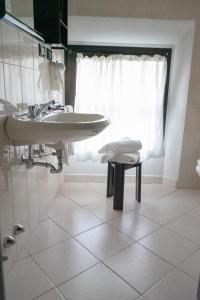 uma casa de banho branca com um lavatório e um banco em Hotel Italia em Porretta Terme