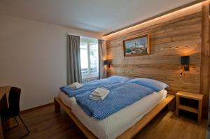 ein Schlafzimmer mit einem Bett mit einer Holzwand in der Unterkunft Haus Matten, Apartment Breithorn in Zermatt
