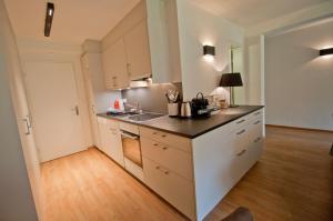 eine Küche mit weißen Schränken und einer schwarzen Arbeitsplatte in der Unterkunft Haus Matten, Apartment Breithorn in Zermatt