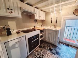 Una cocina con gabinetes blancos y piso de baldosas. en Appartement T6. Emplacement et vue mer d'exception, en Collioure