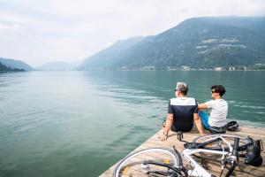 Zwei Männer sitzen auf einem Steg auf einem See in der Unterkunft Wellness Landhaus Parth in Ossiach