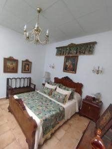 1 dormitorio con cama y lámpara de araña en Casa Doña Gumersinda, en San Carlos del Valle