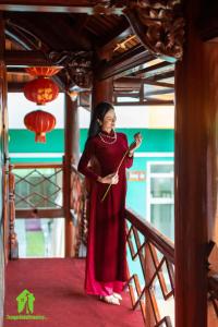 Una donna con un vestito rosso in piedi su una scala di Trang An Ao Dai Homestay a Ninh Binh