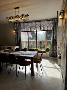 a dining room with a table and chairs and a large window at Füle-Müle Élményház in Füle