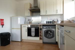 a kitchen with a washing machine and a refrigerator at Guest Homes - Axial Apartment in Colchester