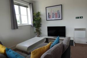 uma sala de estar com um sofá e uma televisão de ecrã plano em Guest Homes - Axial Apartment em Colchester