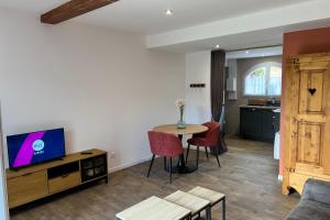 a living room with a tv and a table with chairs at Studio Lac chalain 30 m2 piscine chauffe in La Châtelaine