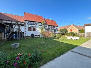 ein Haus mit einem Garten mit Spielplatz in der Unterkunft Corps de ferme alsacien in Grassendorf