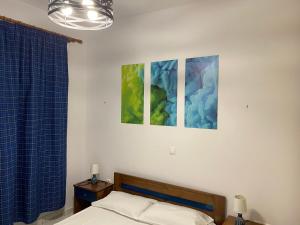 a bedroom with a bed and two paintings on the wall at Palmos Self-Catering Apartment in Kastraki