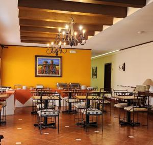 ein Esszimmer mit Tischen und Stühlen und einer gelben Wand in der Unterkunft Hotel Villa Terra in San Salvador