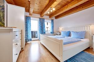 Schlafzimmer mit einem weißen Bett und blauen Vorhängen in der Unterkunft Ferienwohnung an der Ammer in Oberammergau