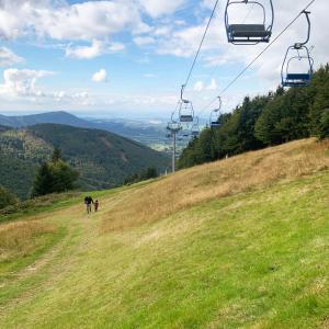 a couple of people walking on a hill with a chair lift at Apartmány pod Kněhyní - BESKYDY in Horní Bečva