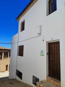 a white building with a brown door on it at Alojamiento Rural Mirador del Valle in Baños de la Encina