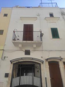 ein weißes Gebäude mit einem Balkon und zwei Fenstern in der Unterkunft Dimora Kettino in Mola di Bari