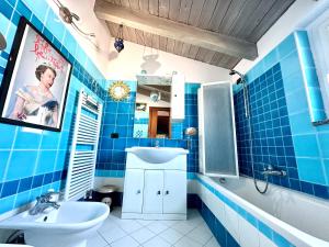 a blue tiled bathroom with a sink and a mirror at The Style Studio in Milan
