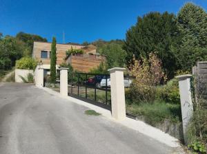 une clôture sur le côté d'une route avec une maison dans l'établissement Maison d'architecte avec vue sur Sens, à Paron