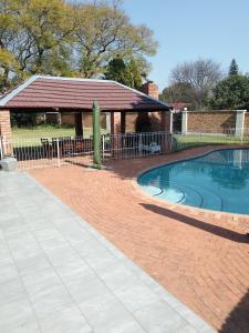 uma piscina com um gazebo num quintal em Just B Zone Guest House em Joanesburgo