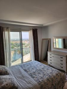 een slaapkamer met een bed en een groot raam bij Kantaoui appartement haut de gamme in Hammam Sousse