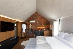 a bedroom with a large white bed and a brick wall at NÖR Hotel & SPA in São Roque