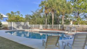a pool with chairs and palm trees in a yard at Seashine and Sunkises - Great pricing near Seaside in Santa Rosa Beach