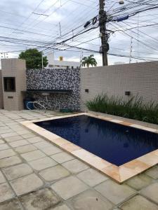 uma pequena piscina num quintal com uma parede de tijolos em Apartamento aconchegante no Bessa em João Pessoa