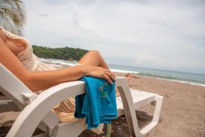 Una donna seduta su una sedia in spiaggia di Leyenda Boutique Hotel & Spa a Sámara