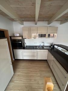 eine Küche mit weißen Schränken und einem Waschbecken in der Unterkunft Ferienwohnung mit Balkon in Oberelsbach