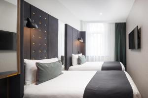 a hotel room with two beds and a tv at Point A Hotel London Kings Cross – St Pancras in London