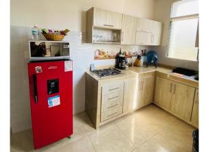 uma cozinha com um frigorífico vermelho e armários de madeira em Apartamento Familiar Buga - Basílica señor de los milagros em Buga