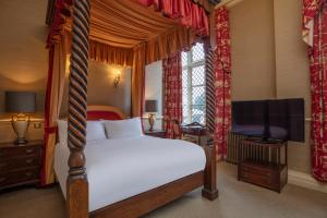 a bedroom with a canopy bed and a television at Crewe Hall Hotel & Spa - Cheshire in Crewe