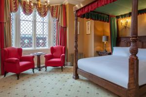a bedroom with a bed and two red chairs at Crewe Hall Hotel & Spa - Cheshire in Crewe