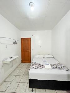 HOTEL AVENIDA في بيليم: غرفة بيضاء مع سرير وحمام