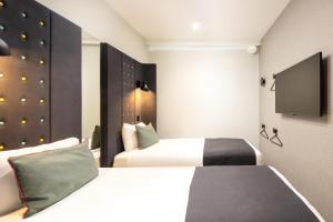 a hotel room with two beds and a flat screen tv at Point A Hotel London Kings Cross – St Pancras in London