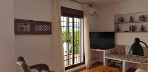 a living room with a tv and a couch and a window at Casas de Almajar in Prado del Rey