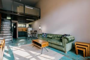 a living room with a green couch and a table at Loft apartmány FABRIKA in Vyhne