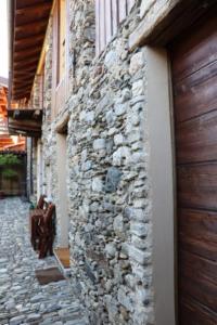 a stone wall next to a building with a door at Cà de sass 1891 in Vezzo