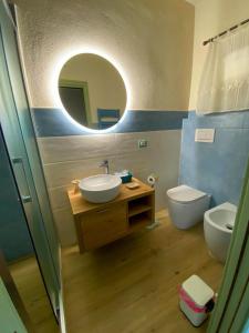 bagno con lavandino, servizi igienici e specchio di I Due Cipressi a Torrenieri