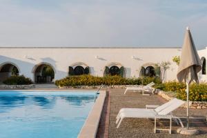 a resort with a swimming pool and chairs and an umbrella at Masseria Gorgognolo in Ostuni