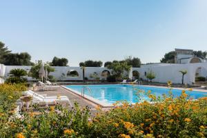a swimming pool in a garden with flowers at Masseria Gorgognolo in Ostuni