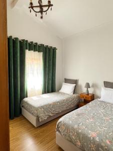 a bedroom with two beds and a window with green curtains at Quinta das Covas - Trancoso in Trancoso