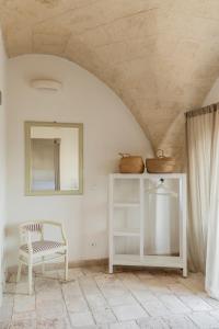 a white room with a chair and a mirror at Masseria Gorgognolo in Ostuni
