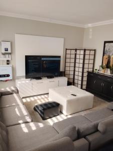 uma sala de estar com um sofá e uma televisão de ecrã plano em Just B Zone Guest House em Joanesburgo