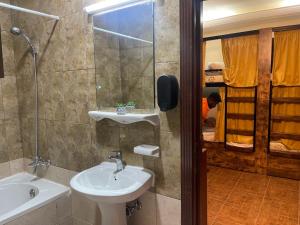 a bathroom with a sink and a mirror and a tub at The Villa Hostel Abu Dhabi in Abu Dhabi