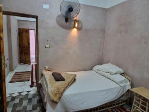 - une chambre avec un lit et un ventilateur mural dans l'établissement quiet home, à Siwa