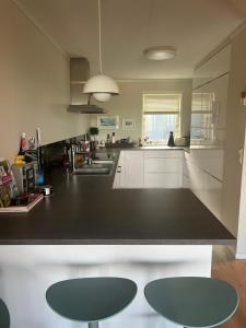 a kitchen with a black counter and two stools at Buvika Panorama 