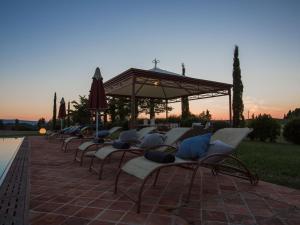 a row of chairs with a gazebo and the sunset at Pleasant villa in Peccioli with private swimming pool in Montelopio